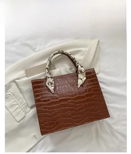 Detail of coffee brown crocodile pattern leather handbag with printed silk scarf handle