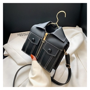 Detail of creative black jacket-style crossbody bag with contrast stitching and mini hanger