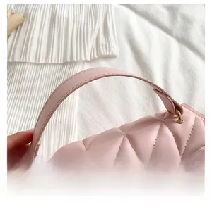 Close-up of pink quilted faux leather handbag handle with gold metal buckles