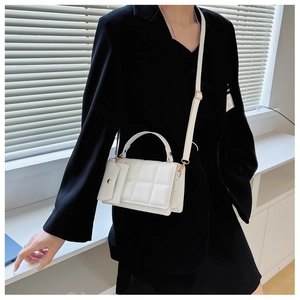 Detail showing white quilted square handbag with matching mini pouch on a black suit