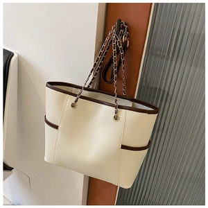 Detail of cream tote bag with brown trim and elegant gold chain shoulder strap