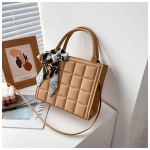 Gros plan du sac cabas camel élégant avec texture matelassée et foulard en soie