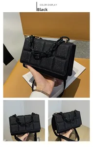 Detail view of black quilted crossbody bag with chunky chain strap and glitter texture