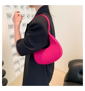 Detail of rose red crescent bag with crocodile texture and silver metal hardware