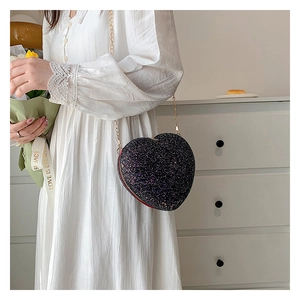 Close-up of a heart-shaped crossbody bag featuring black glitter and a gold chain strap