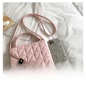 Close-up of pink quilted crossbody bag with gold lock and textured leather stitching