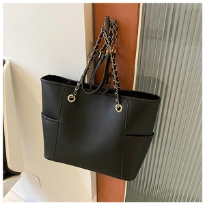 Detail of black PU leather tote bag with gold chain strap and functional side pocket