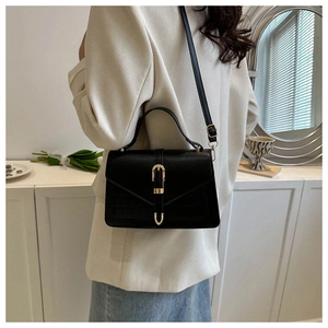 Detail of black crocodile texture handbag featuring a gold U-shaped buckle and strap