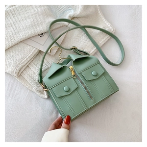 Detail of unique green jacket-shaped shoulder bag featuring a mini golden clothes hanger