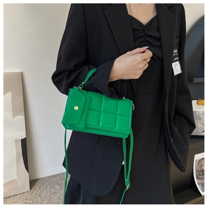 Dettaglio della borsa trapuntata verde vivace con bottone a pressione dorato sulla tasca