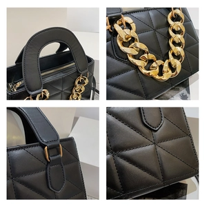 Detail view of black quilted faux leather handbag with gold chain handle and zipper