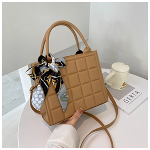 Détail d'un sac à main carré marron avec un foulard en soie décoratif sur la poignée