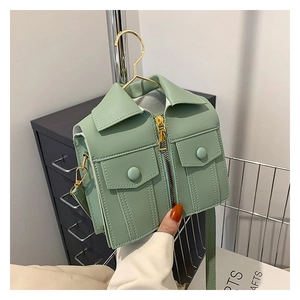 Detail of mint green jacket-shaped crossbody bag with gold zipper and lapel features