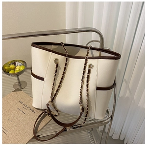 Detail of cream tote bag with dark brown edges and golden chain leather strap