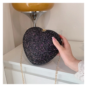 Detail of heart-shaped clutch bag featuring black sequins and golden metal chain