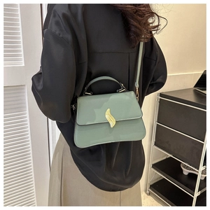Detail of macaron green trapezoid bag featuring a golden leaf clasp and leather texture