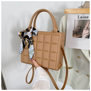 Détail d'un sac à main matelassé marron clair avec foulard en soie décoratif sur l'anse