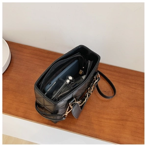 Top view of spacious interior of black quilted bag with chain handle and phone storage