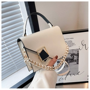 Detail view of cream handbag featuring a dual-tone square lock and braided chain strap