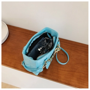 Close-up of light blue quilted bag interior with zipper pocket and metal chain strap