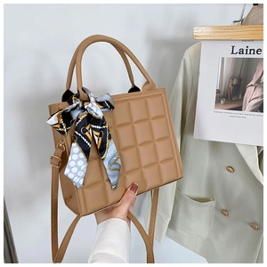 Détail d'un sac à main matelassé beige clair orné d'un foulard en soie imprimé élégant