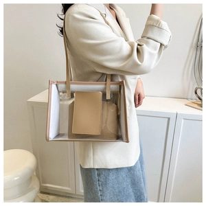 Detailed side view of clear PVC tote with beige inner pouch worn on a shoulder