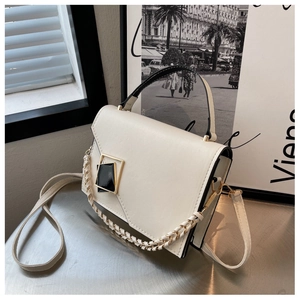 Close-up of cream leather crossbody bag featuring geometric gold and black metal buckle