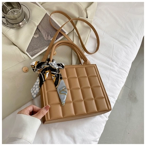 Détail du sac à main camel avec texture quadrillée et foulard en soie sur la poignée