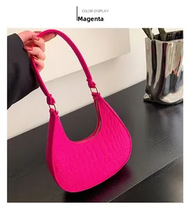 Dettaglio della borsa a mezzaluna fucsia con trama a coccodrillo e fibbie dorate