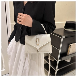 White crossbody Kelly bag with crocodile pattern detail and gold horseshoe buckle on model