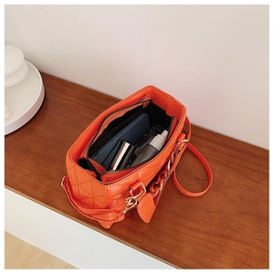Internal view of orange quilted handbag showing large capacity and zipper pocket