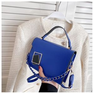 Royal blue leather handbag with gold geometric buckle and woven chain strap detail