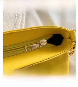 Detail shot of a yellow quilted PU handbag showing smooth metal zipper closure