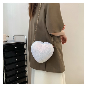 Detail of white iridescent heart-shaped crossbody bag with glitter finish and gold chain