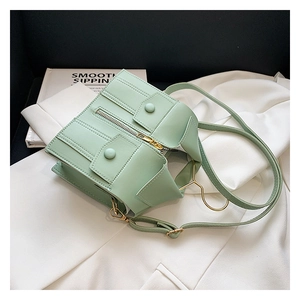 Detail of mint green jacket-style crossbody bag with gold zippers on white blazer