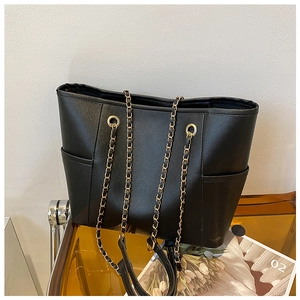 Close-up of black PU leather tote bag featuring golden chain strap and side pocket detail