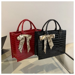 Detail of red and black crocodile embossed tote bags with decorative silk scarves