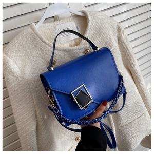 Detail of bright blue leather handbag featuring a square geometric gold metal magnetic buckle