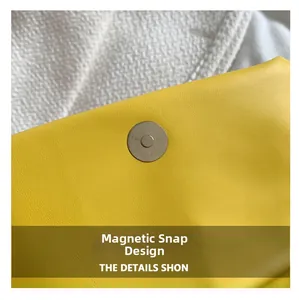 Detail of silver magnetic buckle closure on yellow lychee texture faux leather bag