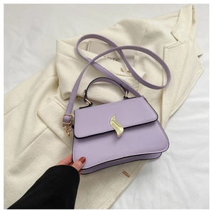 Detail of lavender trapezoid bag with golden wave clasp on beige blazer fabric