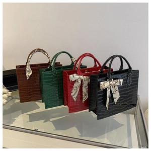 Detail showing the group of crocodile pattern tote bags in four classic colors with scarves