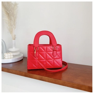 Detail shot of a red quilted leather handbag with gold metal hooks and handles
