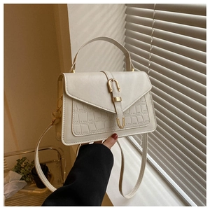 Close-up of cream square bag with crocodile pattern and gold horseshoe buckle detail