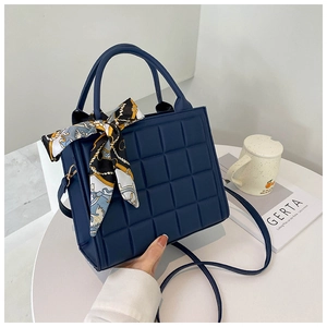 Détail du sac à main matelassé bleu marine avec foulard élégant et motif à carreaux