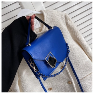 Detail of royal blue leather handbag featuring geometric gold buckle and chain strap