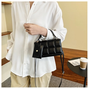 Quilted black crossbody bag with detachable coin purse shown on model's shoulder