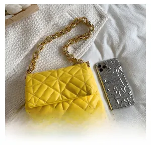 Close-up of bright yellow quilted shoulder bag with chunky gold acrylic chain strap