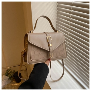 Detail of beige faux leather handbag featuring crocodile pattern texture and metallic clasp