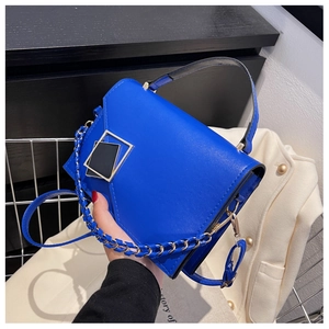 Detail of Klein blue leather handbag featuring geometric metal buckle and chain strap