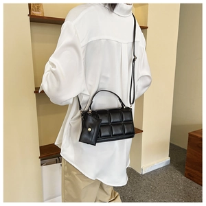 Detail of black quilted shoulder bag with matte finish and matching mini coin purse